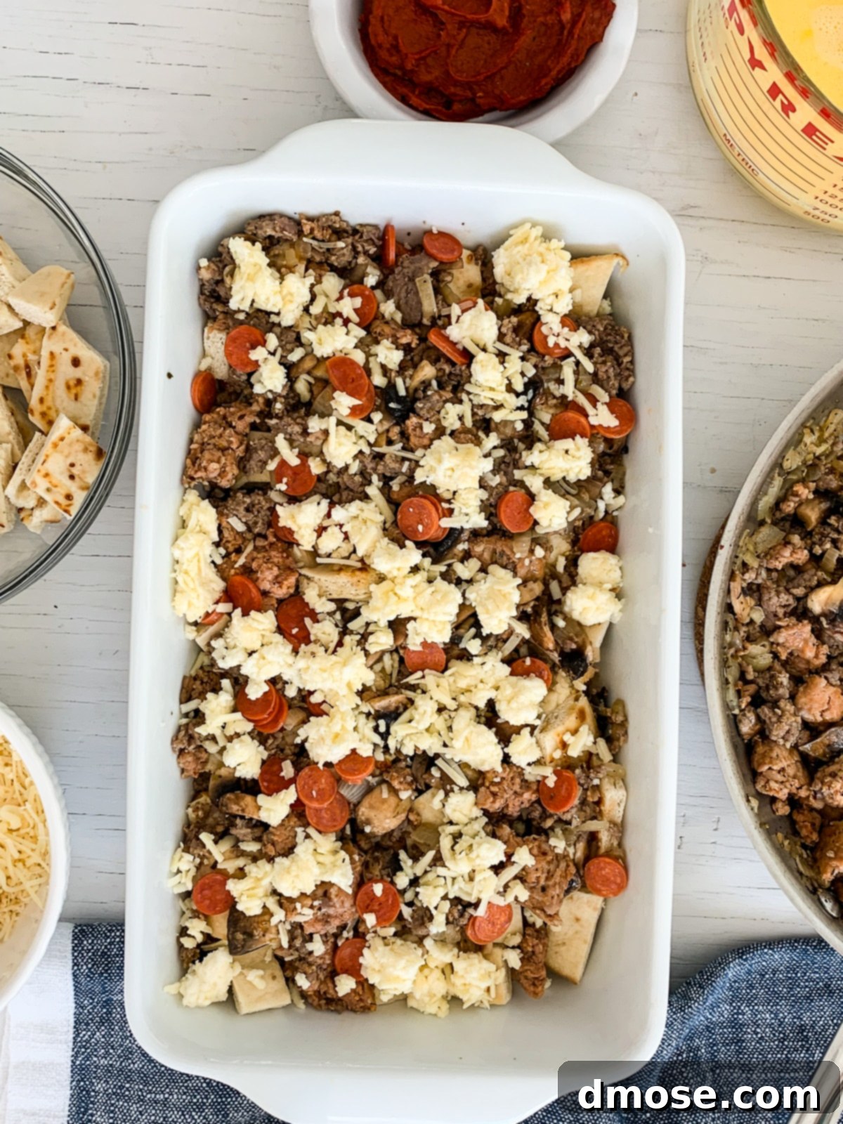 Cheesy Pizza Breakfast Bake 8 Layering the ingredients in a white baking dish for the breakfast casserole.