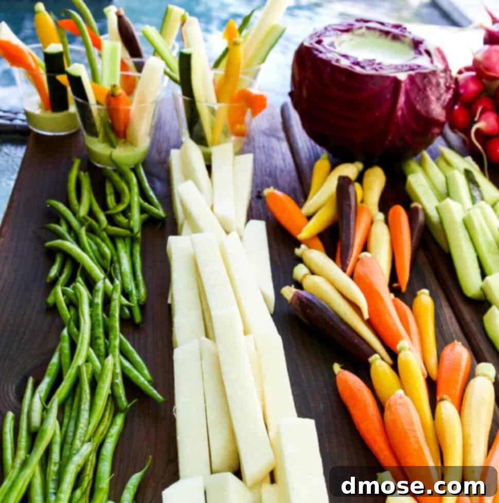 Colorful Veggies & Zesty Dip 9 A cutting board with crudites and dip with bright colored vegetables cut into strips and sticks.